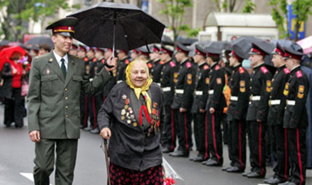 Karininkas laiko skėtį virš II-ojo Pasaulinio karo veteranės per Pergalės dienos iškilmes Kijeve. 