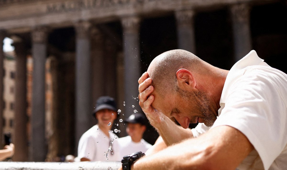 Turistas Romoje po ilgo laukimo eilėje bando atsigaivinti prie fontano 