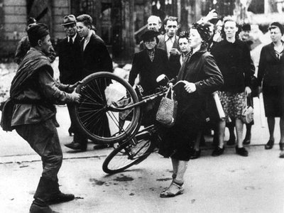 Raudonarmietis plėšia iš vokietės dviratį. Berlynas, 1945 m. Iš Horsto Gerlacho knygos „Raudonasis košmaras“
