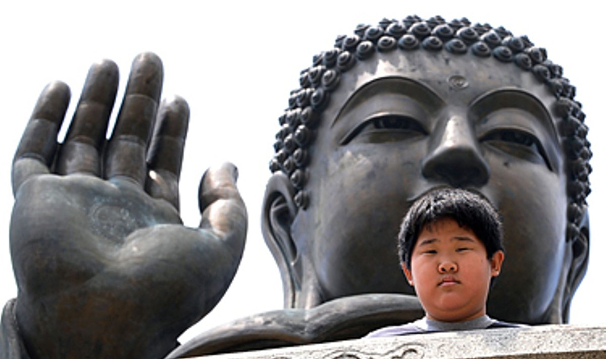 Berniukas Honkonge pozuoja šalia Budos statulos.