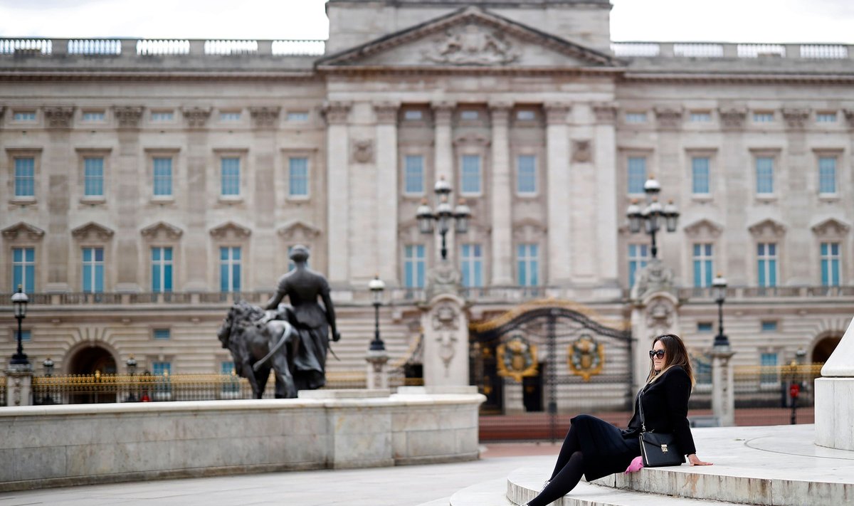 Moteris sėdi ant laiptų priešais Bekingemo rūmus Londone