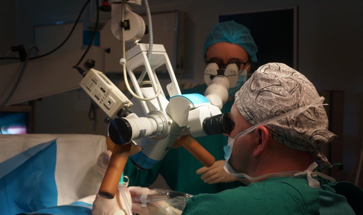 Gydytojas otochirurgas Giedrius Gylys atlieka operaciją vienai iš dvynių.