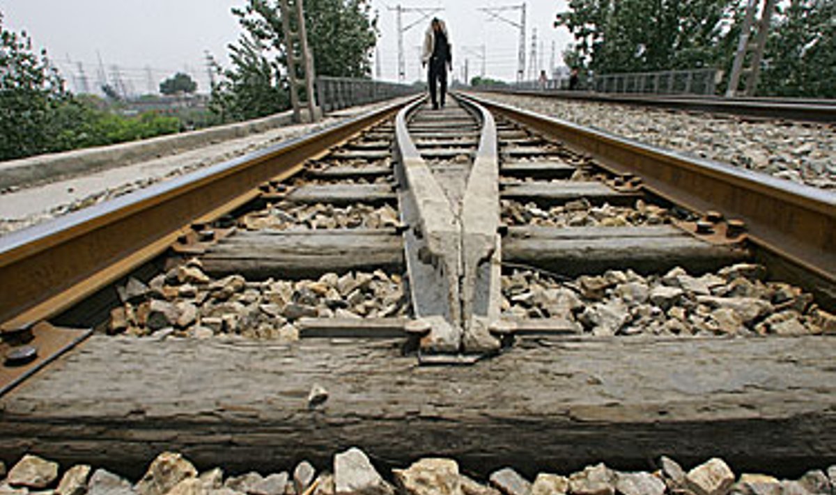 Žmogus eina uždarytu geležinkeliu Pekino priemiestyje.