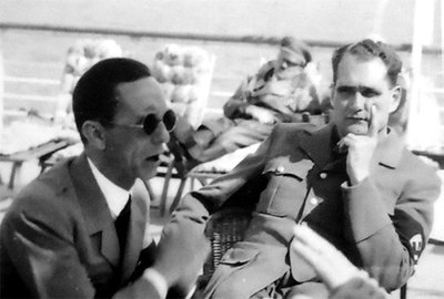 Kiek siurrealistinis Josepho Goebbelso ir Rudolfo Hesso vaizdas Berchtesgadene. Už jų matyti ant šezlongo snaudžiantis Hitleris.