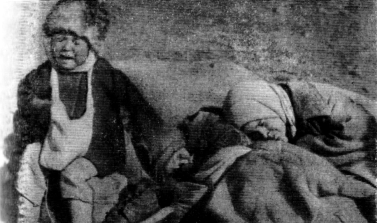 Bado išsekintas vaikas greta iš bado mirusios šeimos. Knygos „Sielvarto derlius: sovietinė kolektyvizacija ir teroras badu“ iliustracija