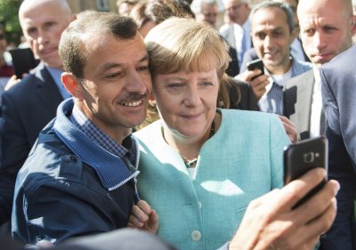 Vokietijos kanclerė A. Merkel pozuoja nuotraukai su pabėgėliu