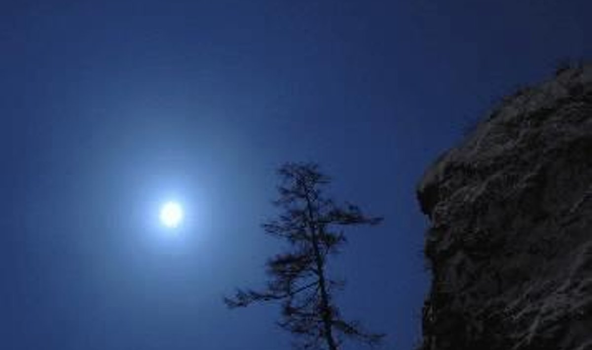Mėnulis šviečia virš uolos Sibiro taigoje (Rusija). 
