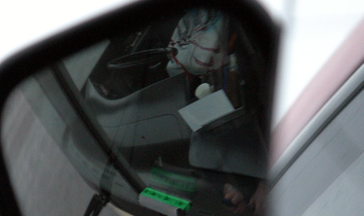 Troleibuso veidrodėlyje matyti kaip vairuotojas plauna priekinį stiklą