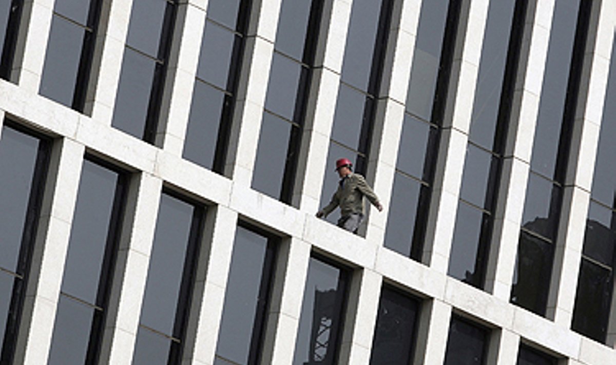 Darbininkas vaikšto ant Pekine esančio dangoraižio. 