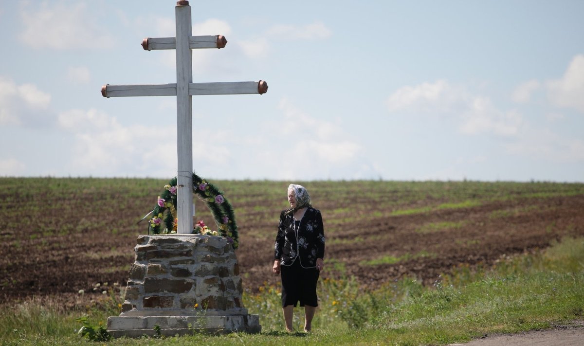 MH17 tragedijos vietoje žmonės neša vainikus ir stato kryžius