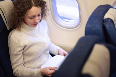 Moteris sėdi lėktuve prie lango
