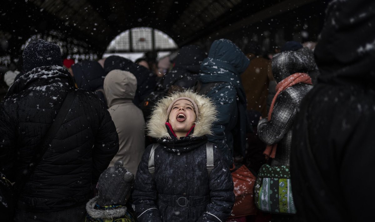 Sekmadienį, 2022 m. vasario 27 d., Lvove, Vakarų Ukrainoje, mergaitė gaudo snaiges, laukdama traukinio į Lenkiją Lvovo geležinkelio stotyje.