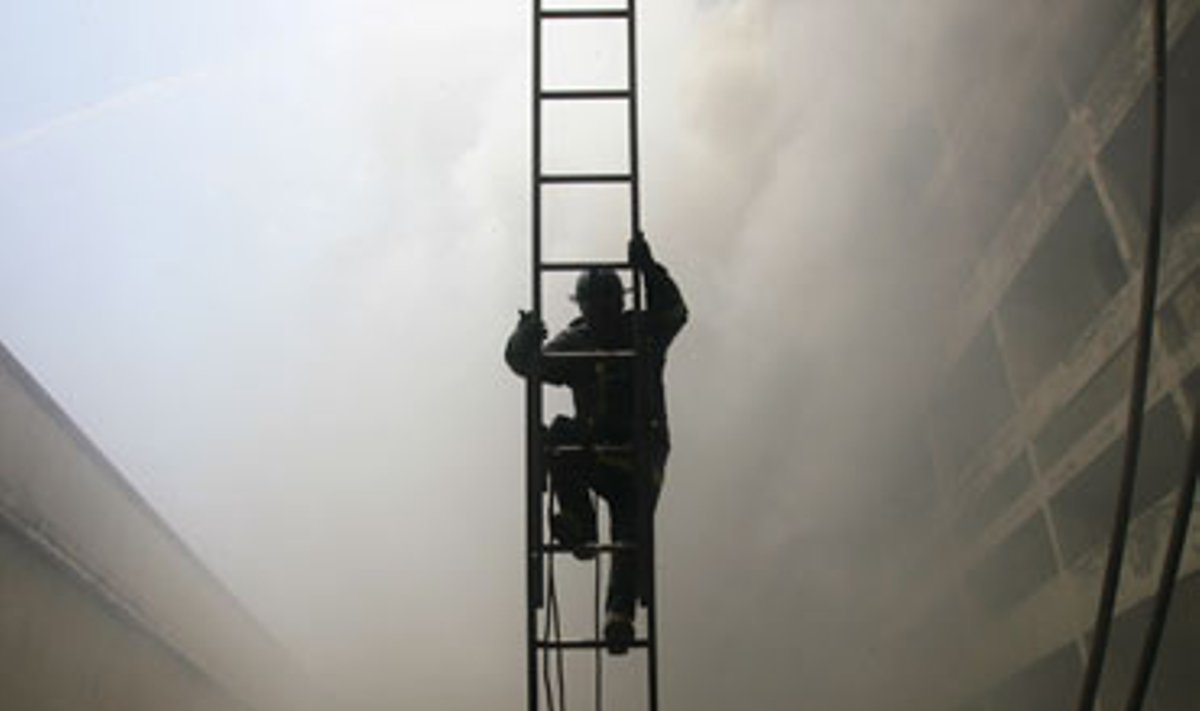 Gaisrininkas lipa kopėčiomis per gaisrą Maniloje (Filipinai).
