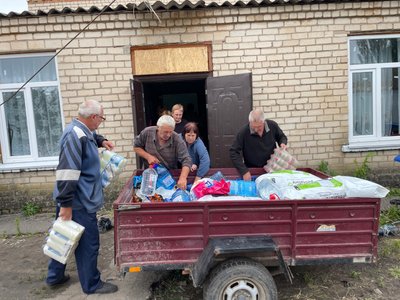 Sadovo gyventojai padėjo iškrauti atvežtą paramą, bet kartu baiminosi apšaudymo – išvakarėse atlėkusi bomba išvertė mokyklos tvorą (Eldorado Butrimo nuotr.)