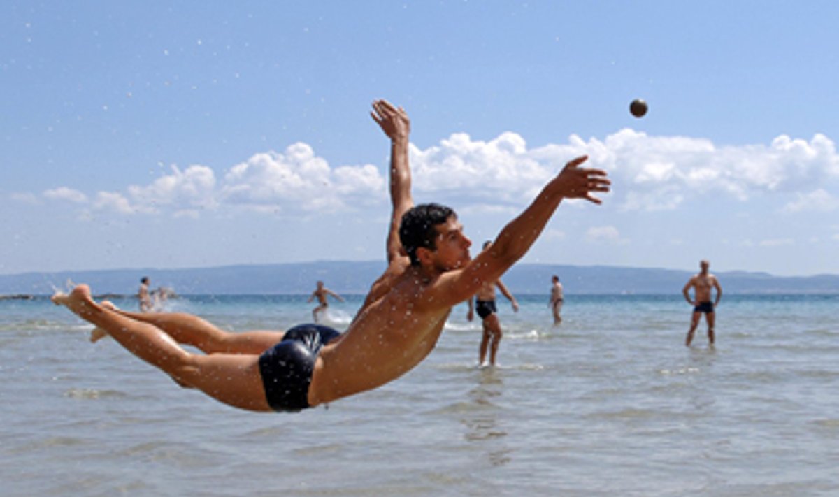 Jaunas vyras žaidžia su kamuoliu Kroatijos paplūdimyje. 
