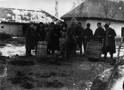 Sovietų saugumas ir kaimo aktyvistai atima iš valstiečio slėptus grūdus. Keletas aktyvistų rankose laiko „zondus“ 