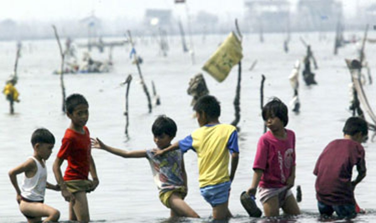 Per atoslūgį Manilos įlankoje dūksta vaikai, kol jų tėvai renka valgomus moliuskus.