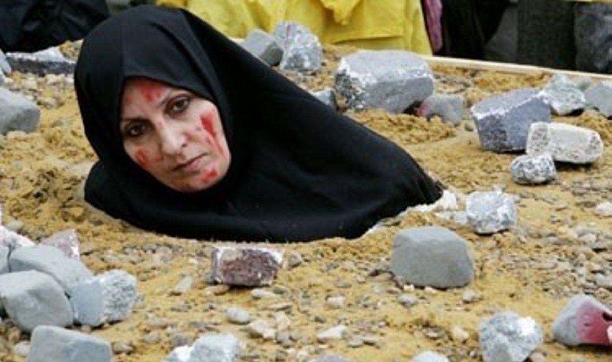 Iranietė moteris, vaizduodama akmenimis užmuštą auką, protestuoja Briuselyje, kur renkasi ES užsienio reikalų ministrai svarstyti Irano pasiūlymo bendradarbiauti dėl branduolinės programos. 