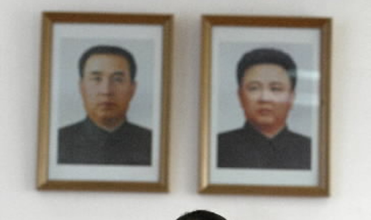 Šiaurės Korėjos mokinė klasėje dainuoja stovėdama priešais dviejų valstybės lyderių - buvusiojo Kim Il-Sungo (kairėje) ir dabartinio Kim Jong-Ilo -   portretus.