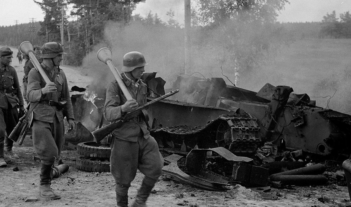 Suomių kariai eina pro pamuštą sovietų tanką 