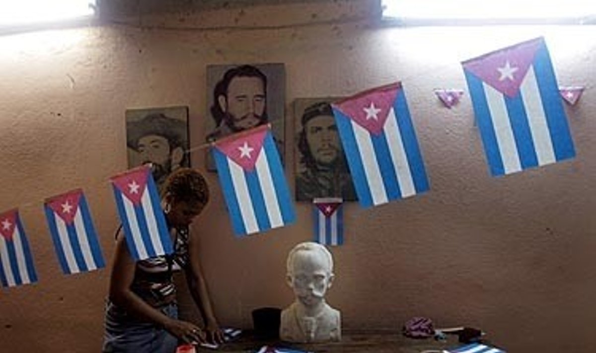 Kubietė lanksto vėliavas stovėdama greta šalies prezidento Fidelio Castro ir Kubos didvyrių Camilo Cienfuegos bei Argentinoje gimusio Ernesto “Che” Guevaros portretų. 
