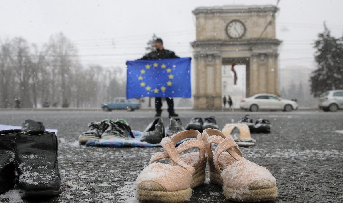 Vyras su ES vėliava dėl prastų pragyvenimo sąlygų protestuoja Kišiniove. Batai simbolizuoja išvykusius Moldovos emigrantus