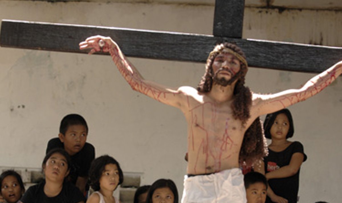 Filipiniečiai vaikai stebi kaip vietos katalikai atkartoja Jėzaus Kristaus patirtas kančias.