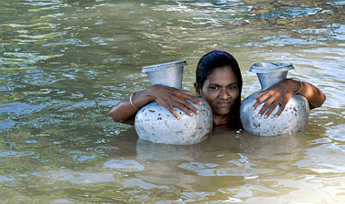 Potvynių niokojamo Bangladešo gyventoja brenda su ąsočiais geriamam vandeniui. 