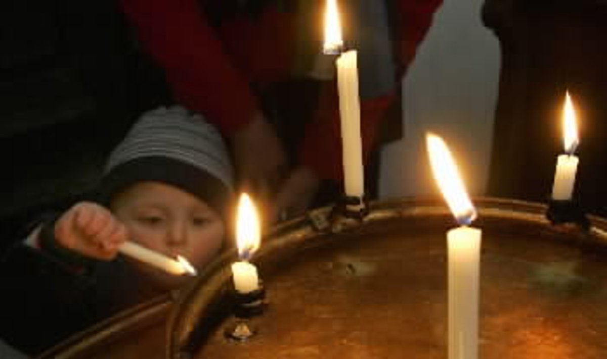 Mergytė Miuncheno bažnyčioje bando uždegti žvakelę už sunkiai sergantį Popiežių Joną Paulių II-ąjį.