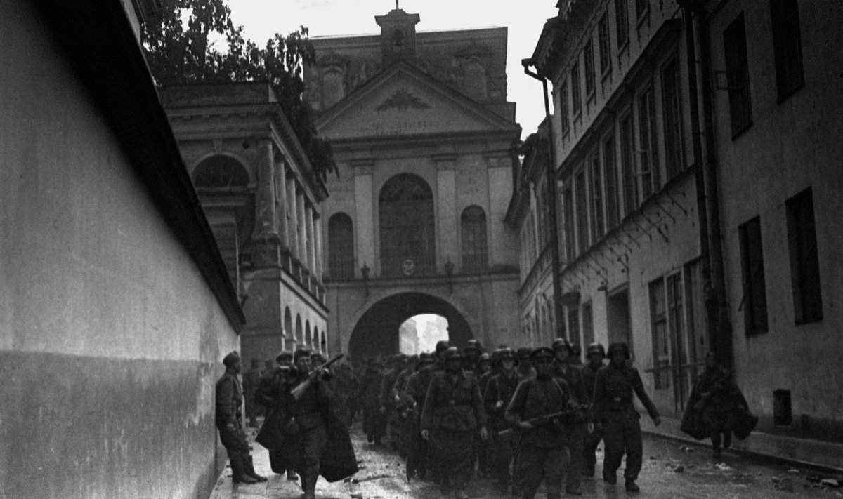 Vokiečių belaisviai, su ginkluota palyda vedami pro Aušros vartus. Greičiausiai fotografuota 1944 m. liepos 13 arba 14 d., nes tomis dienomis lijo, o nuotraukoje gatvės grindinys šlapias.
