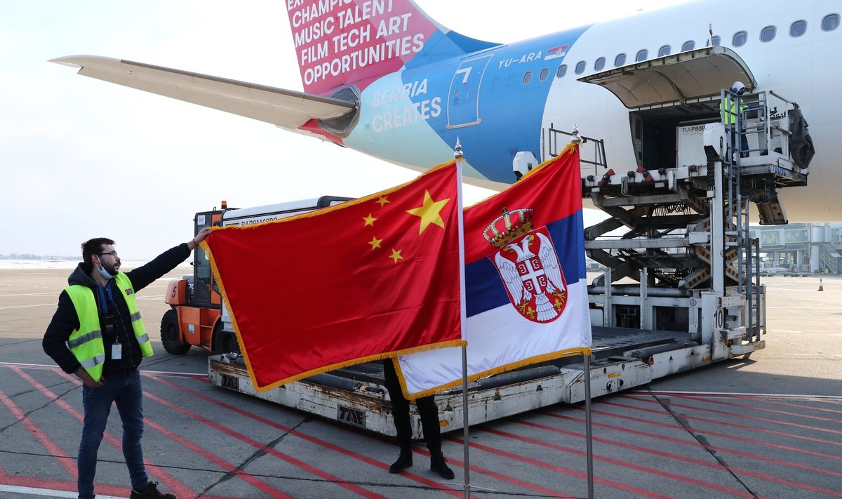 A man holds China s flag next to Serbia s flag as a plane transporting one million doses of Sinopharm s China National Biotec Group (CNBG) vaccines for the coronavirus disease (COVID-19) arrives at Nikola Tesla Airport in Belgrade, Serbia, January 16, 2021. 