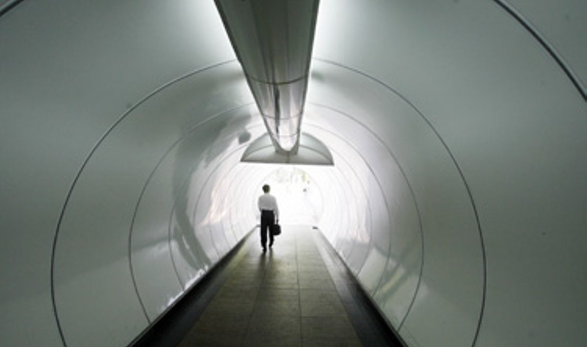 Verslininkas eina tuneliu, esančiu finansiniame Singapūro centre.