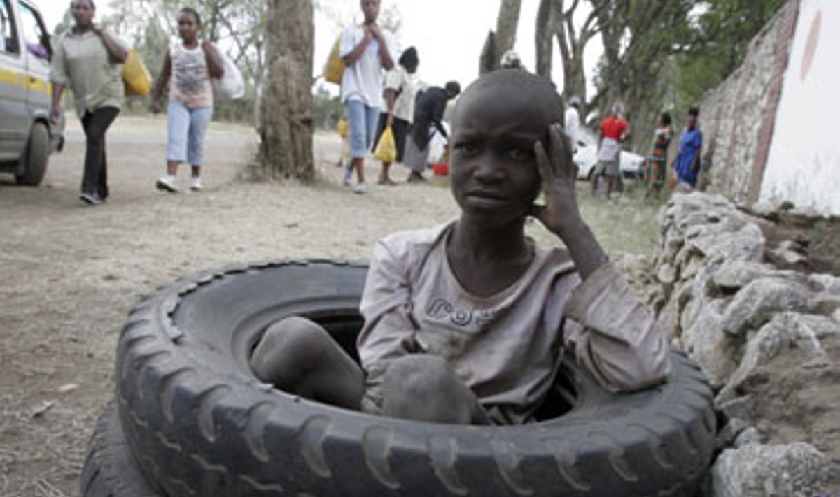 Vaikas ilsisi sėdėdamas panaudotose padangose (Kenija).