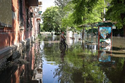 A local resident stands with his bicycle in a flooded street in the town of Kherson,  following flooding caused by damage sustained at the Kakhovka HPP dam, on June 6, 2023. The partial destruction on June 6, of the major Russian-held dam in southern Ukraine unleashed a torrent of water that flooded two dozen villages forcing mass evacuation, sparking fears of a humanitarian disaster near the war's front line. Moscow and Kyiv traded blame for ripping a gaping hole in the Kakhovka dam as expectations built over the start of Ukraine's long-awaited offensive. (Photo by STRINGER / AFP)