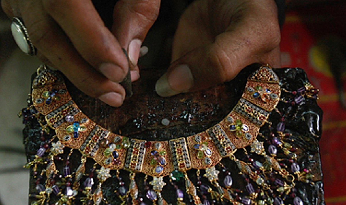Pakistane juvelyras auksu dekoruoja vėrinį.