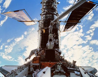 Astronautai iš šatlo „Discovery“ (apačioje) aptarnauja Hablą (viršuje) trečiosios misijos metu 1999 metais. Šaltinis: NASA