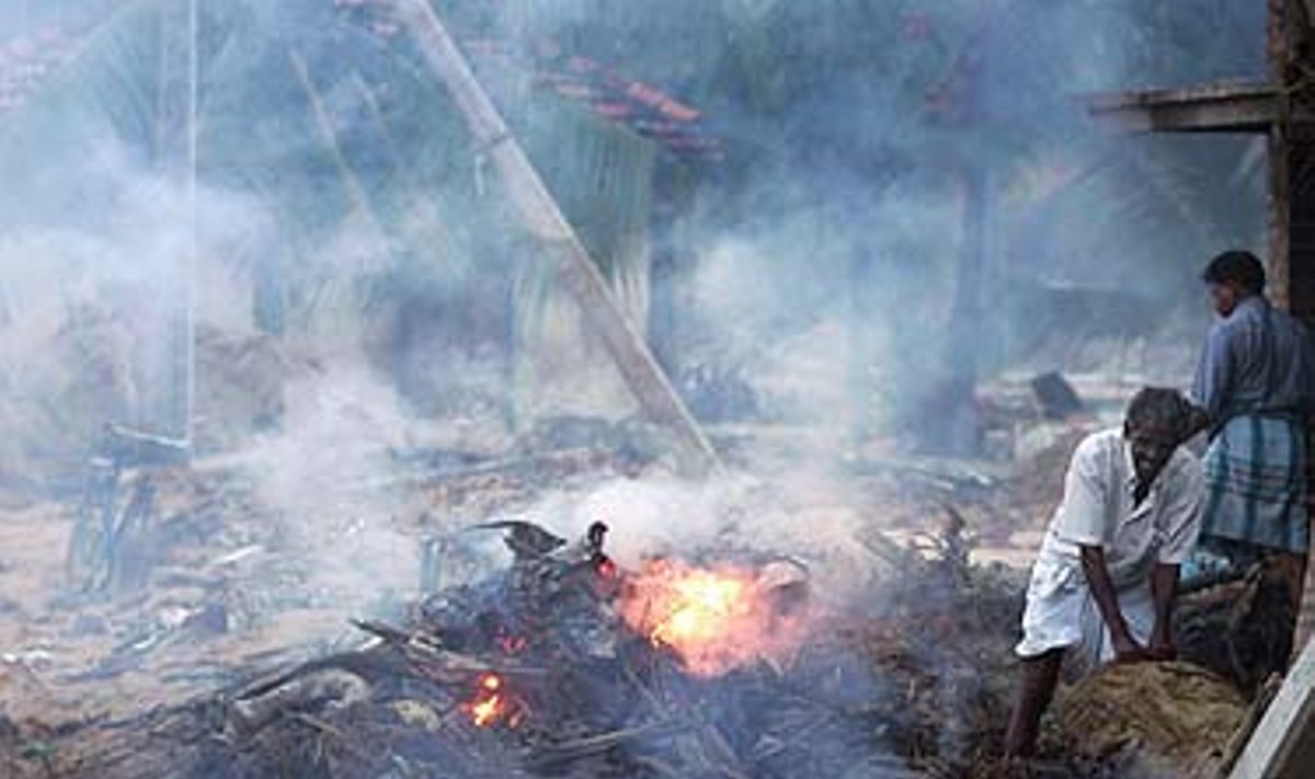Šri Lankos gyventojai degina nereikalingas medžiagas prie cunamio nuniokotų savo namų.