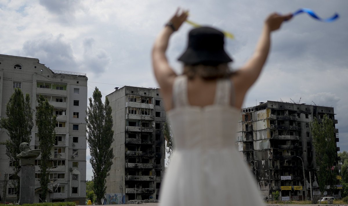 Mergina šoka priešais pastatus, sunaikintus per Rusijos ataką Borodyankoje. Kijevo apylinkės, Ukraina. 2022 m. birželio 21 d. 