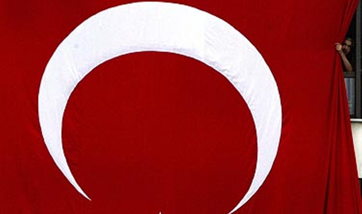 Vyras Turkijoje stebi karinį paradą pro milžinišką šalies vėliavą. Turkijoje paminėtos 82-antrosios Pergalės dienos metinės. 