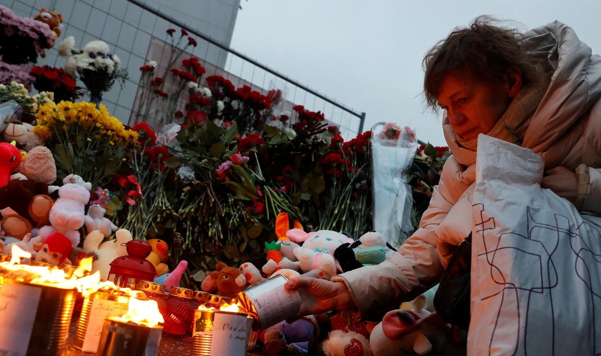 A woman lights a candle at a makeshift memorial to the victims of a shooting attack at the Crocus City Hall concert venue in the Moscow Region, Russia, March 23, 2024. REUTERS/Yulia Morozova