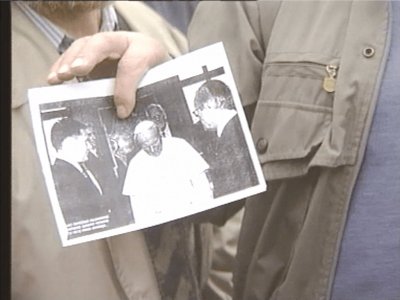Pensininkai prie prezidentūros rodo G.Petriko ir A.Brazausko vizito Vatikane nuotrauką‍(LRT archyvo stopkadras)