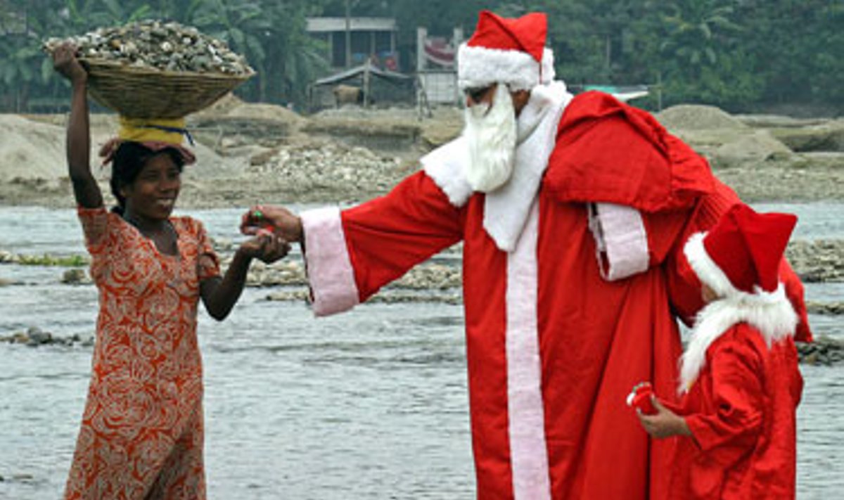 Kalėdų Seneliu apsirengęs vyriškis Indijoje vaišina saldainiais vargingai gyvenančius.