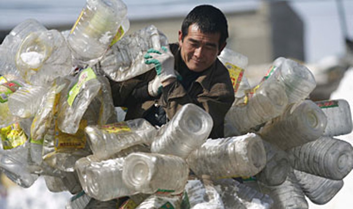 Vyras neša plastikinius butelius, skirtus perdirbimui (Kinija).