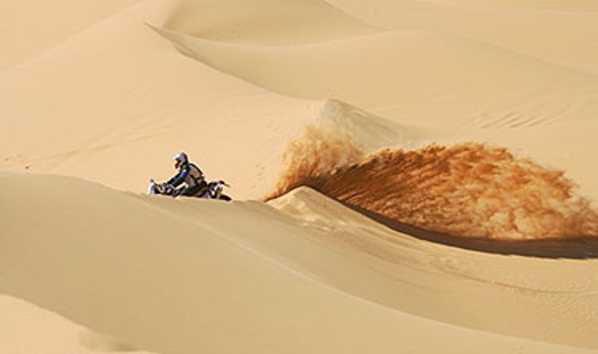 Motociklininkas skrieja per dykumą Dakaro ralyje. 