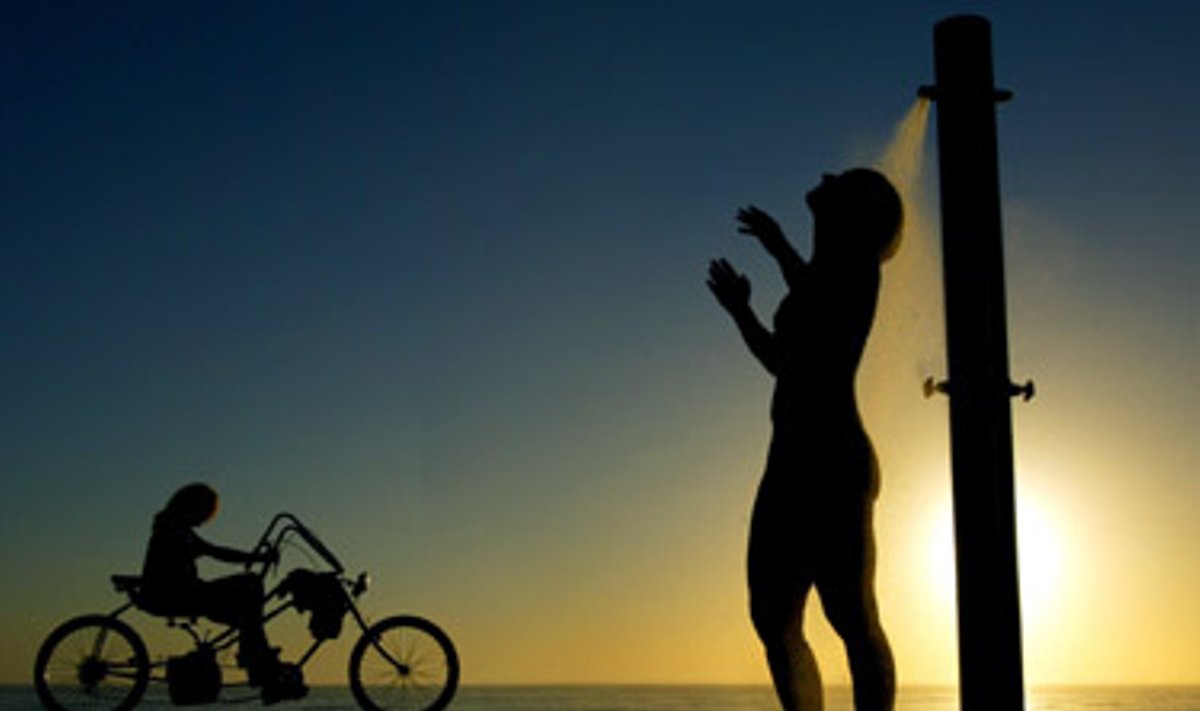 Vakaras Sidnėjaus paplūdimyje: kol pajūriu važiuoja dviratininkas, moteris maudosi po dušu. 