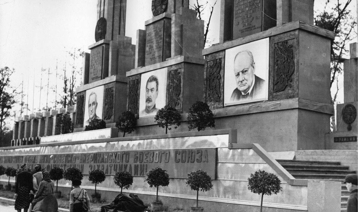 Sąjungininkų vadų portretais papuoštas monumentas. Prie jo – namus praradę vokiečių pabėgėliai. Berlynas. 1945 m. liepa.