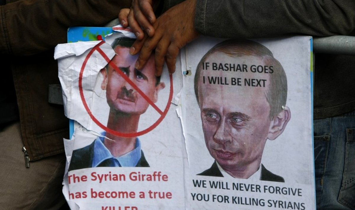 Protestuotojas Sirijoje laiko plakatą su A. Basharo ir V. Putino atvaizdais