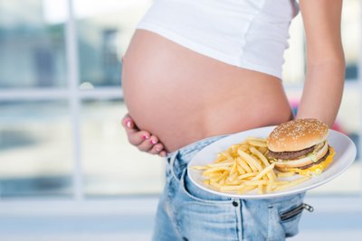 Nėščia moteris valgo greitąjį maistą