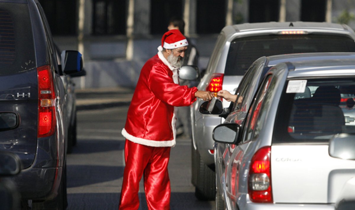 Vyras, apsirengęs kaip Kalėdų senelis, Santjago gatvėje prašo pinigų.