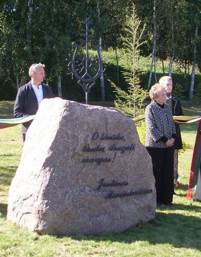Paminklinę saulutę ir užrašą akmenyje iškalė tautodailininkas kalvis Ričardas Grekavičius. Nuotraukoje jis su J. Marcinkevičiaus žmona Genovaite